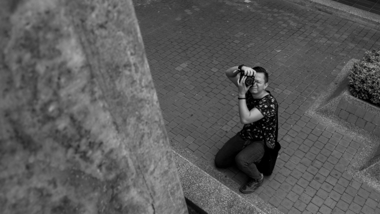 男性がデジタルカメラでモノクロ写真を撮ってる姿