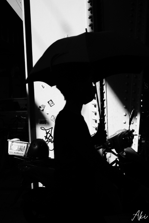 主体の後ろにある光を使って主体を真っ黒にした、傘を持った女性の形